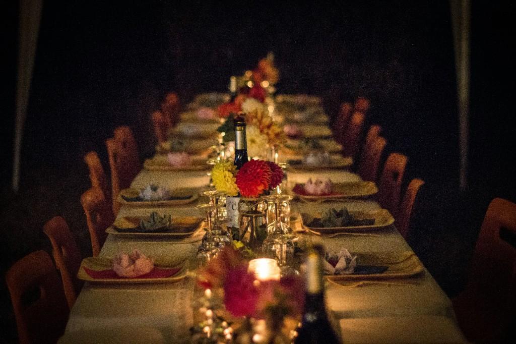 Candlelit banquet table set with flowers, plates, and wine glasses