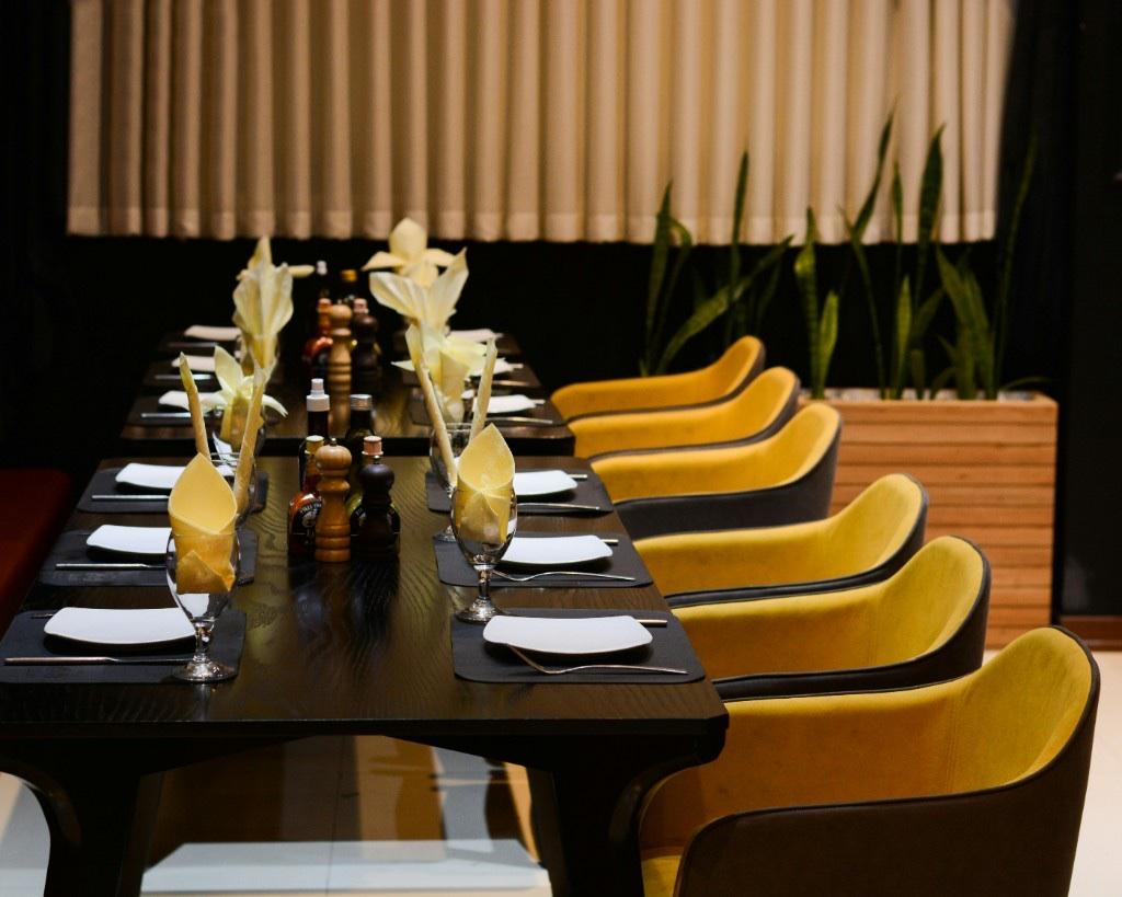 Long restaurant table set with yellow napkins