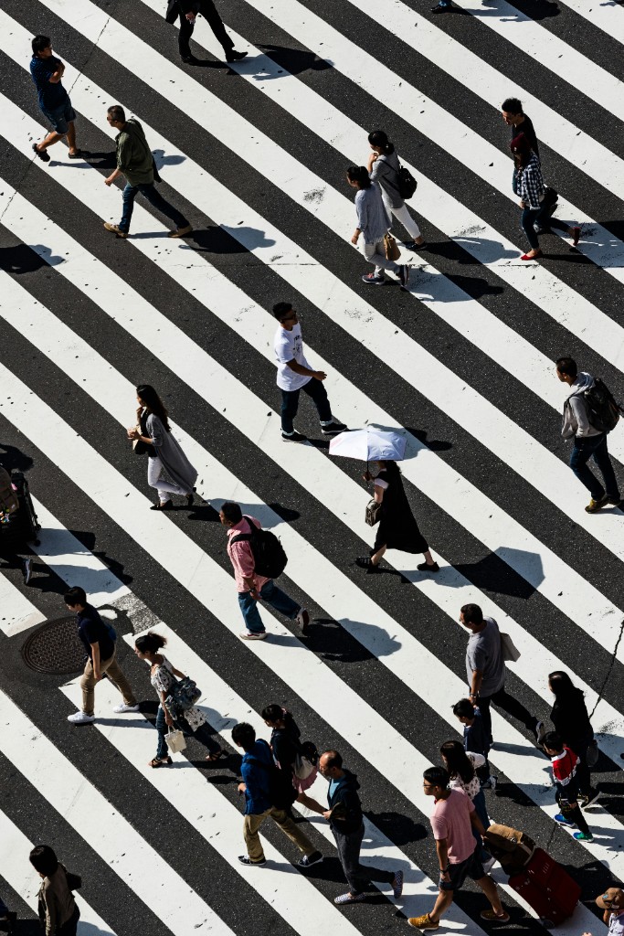 Pedestrians crossing a sunlit striped city crosswalk